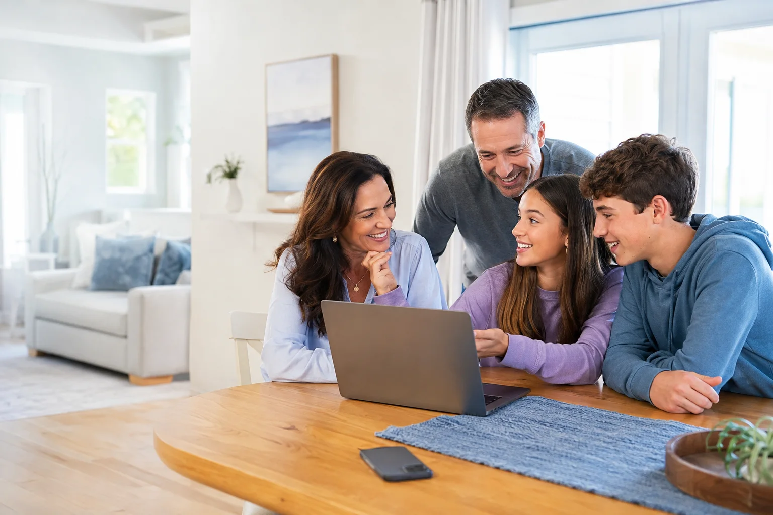 Parents and their teenage children talking together around a laptop